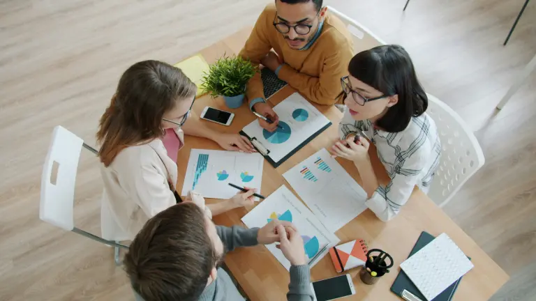 group of professionals sitting at a table looking at charts and graphs